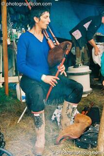 Woman plays a bagbipe by the fireside at Big Green Gathering 2003. Cheddar, Great Britain. © 2003 Photographicon