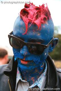 A man with a peeling acrylic painted head in the Lost Vaguess field at Glastonbury Festival 2002. Pilton, Great Britain. © 2002 Photographicon