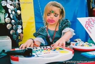 Girl with grotesque make-up plays music for the freak show in the Lost Vagueness field at Glastonbury Festival 2003. Pilton, Great Britain. © 2003 Photographicon