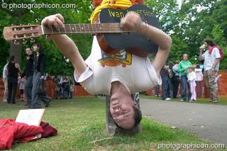 Ivan Inversion plays hanging upside-down at Kingston Green Fair 2005. Kingston Upon Thames, Great Britain. © 2005 Photographicon