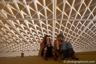 A couple sit in front of large projection of roofing girders at Dr Love's Psychoactive Explosion. London, Great Britain. © 2004 Photographicon