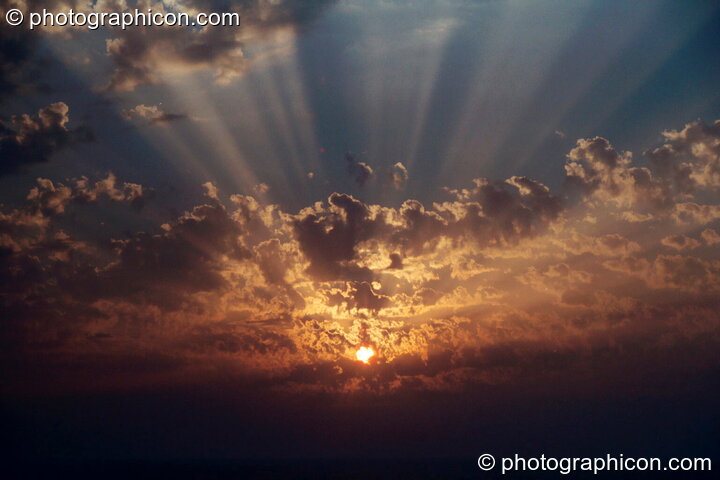 The setting sun through the gaps in the cloud at Agios Pavlos. Greece. © 2002 Photographicon