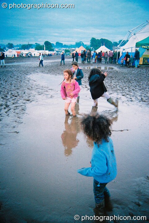 Kids wading through a mud lake at Big Green Gathering 2003. Cheddar, Great Britain. © 2003 Photographicon