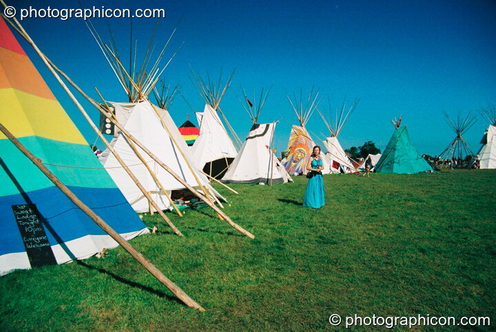 Woman standing in the tipi circle surrounded by a cloudless blue sky at Big Green Gathering 2003. Cheddar, Great Britain. © 2003 Photographicon