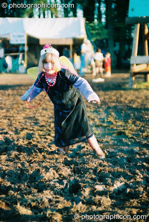 Girl in angel wings and Wellington boots caught in the mud at Big Green Gathering 2003. Cheddar, Great Britain. © 2003 Photographicon