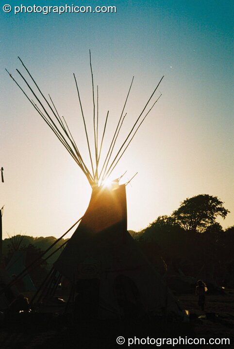 The setting sun framed by tipi poles at Big Green Gathering 2003. Cheddar, Great Britain. © 2003 Photographicon