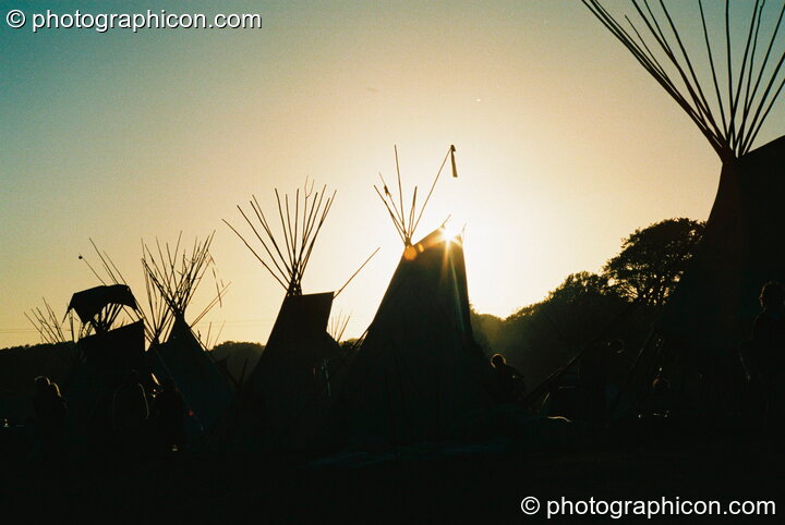 The setting sun framed by tipi poles at Big Green Gathering 2003. Cheddar, Great Britain. © 2003 Photographicon