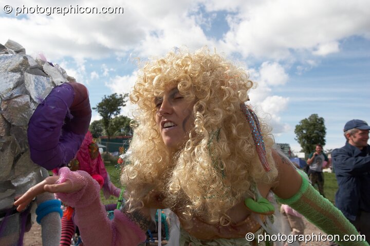 A woman in a wig dances with a fish on a bike at Big Green Gathering 2005. Burrington, Cheddar, Great Britain. © 2005 Photographicon