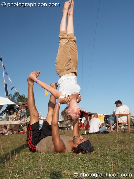 A man lies on his back supporting a woman practicing acrobatics at Big Green Gathering 2007. Burrington, Cheddar, Great Britain. © 2007 Photographicon