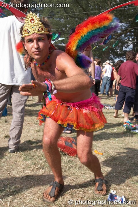 Man wearing orange mini-skirt, fairy wings, and a gold tiara dances by Origin Stage at Glade Festival 2005. Aldermaston, Great Britain. © 2005 Photographicon