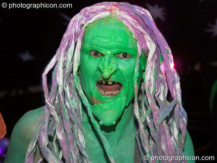 Man in wig and grotesque green makeup dances by the Origin Stage at Glade Festival 2005. Aldermaston, Great Britain. © 2005 Photographicon