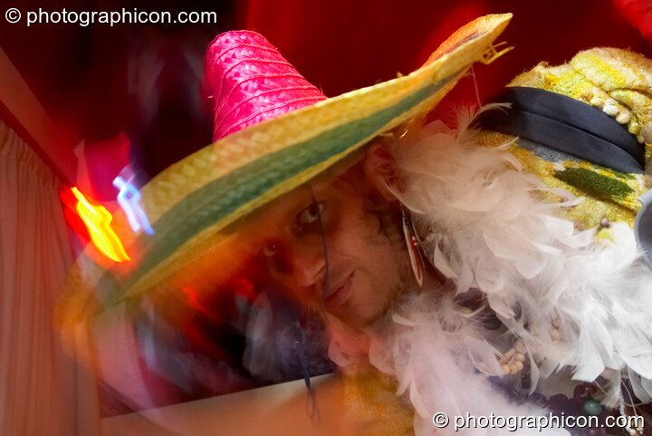 A man in straw hat and feather boa dances in the Boom Bus at Glade Festival 2011. King's Lynn, Great Britain. © 2011 Photographicon