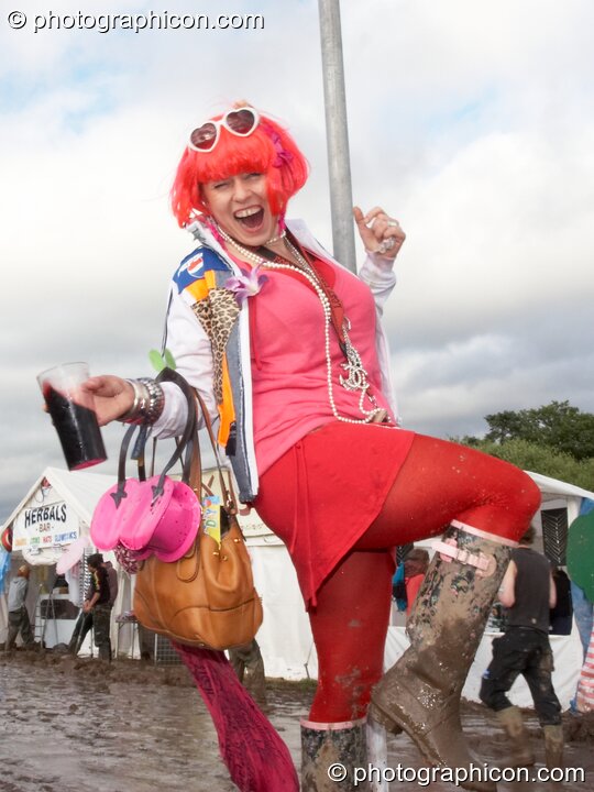 A woman dressed in pink swings on a pole while swigging a pint in the mud at Glade Festival 2007. Aldermaston, Great Britain. © 2007 Photographicon