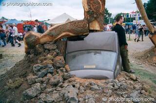 Tree Pirates chainsaw sculpture of a tree burying a car at Glastonbury Festival 2002. Pilton, Great Britain. © 2002 Photographicon