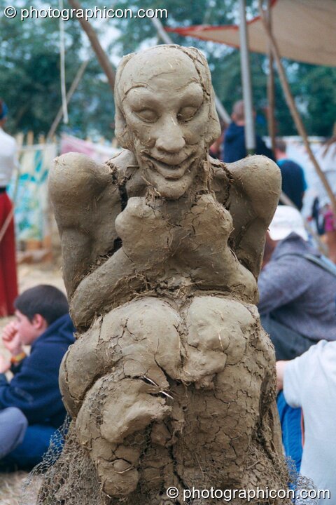A clay sculpture of a person sitting by the fire at Glastonbury Festival 2002. Pilton, Great Britain. © 2002 Photographicon