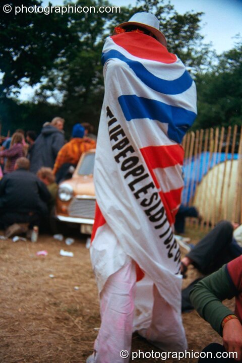 Woman wrapped in large banner for the Peoples Lotto in the Lost Vaguess field at Glastonbury Festival 2002. Pilton, Great Britain. © 2002 Photographicon