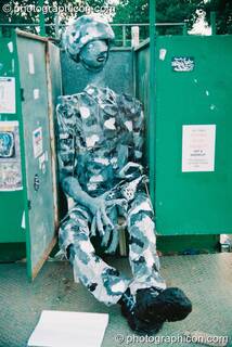 Mannequin dressed in soldier's outfit sitting on a toilet at Glastonbury Festival 2003. Pilton, Great Britain. © 2003 Photographicon
