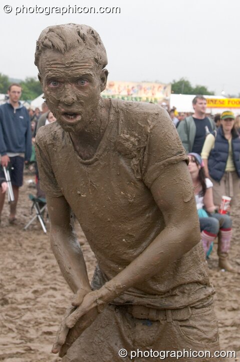 Man wearing a T-shirt is covered head to foot in mud at Glastonbury Festival 2005. Pilton, Great Britain. © 2005 Photographicon