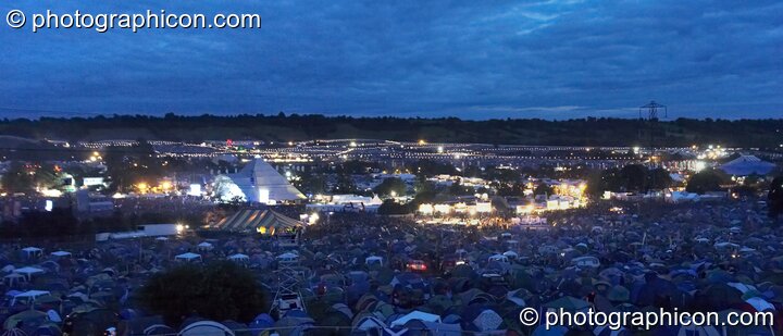 A night panoramic view of Glastonbury Festival 2007 taken from the the camping hill above the pyramid stage. Pilton, United Kingdom. © 2007 Photographicon