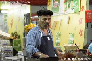 A man in a beret prepares food on a cafe stall at Glastonbury Festival 2008. Pilton, Great Britain. © 2008 Photographicon