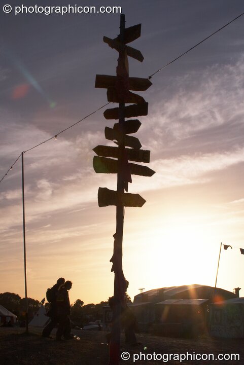 A tall and heavy ladened sign post silhouetted against the setting sun in The Park at Glastonbury Festival 2008. Pilton, Great Britain. © 2008 Photographicon