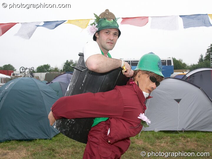 A Green Policeman is carried in a dustbin on the back of his mannequin assistant at Glastonbury Festival 2005. Pilton, Great Britain. © 2005 Photographicon