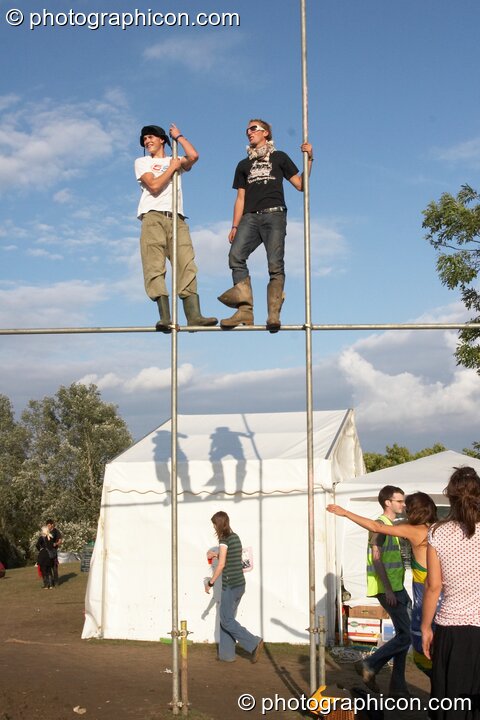 Two men stand on top of staffold poles at the Secret Garden Party 2006. Huntingdon, Great Britain. © 2006 Photographicon