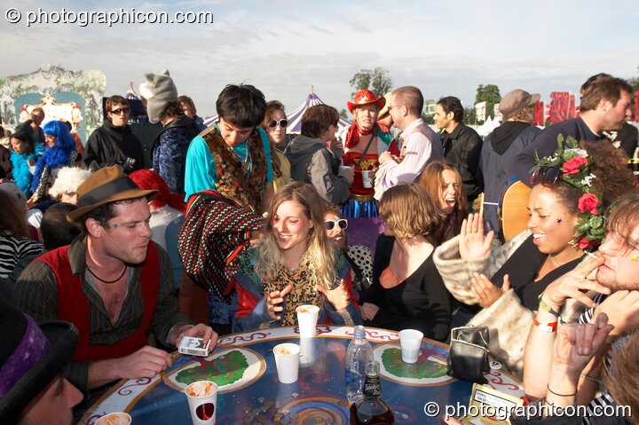 A group of wonky people gather round a table in the early morning sun at the Secret Garden Party 2007. Huntingdon, Great Britain. © 2007 Photographicon