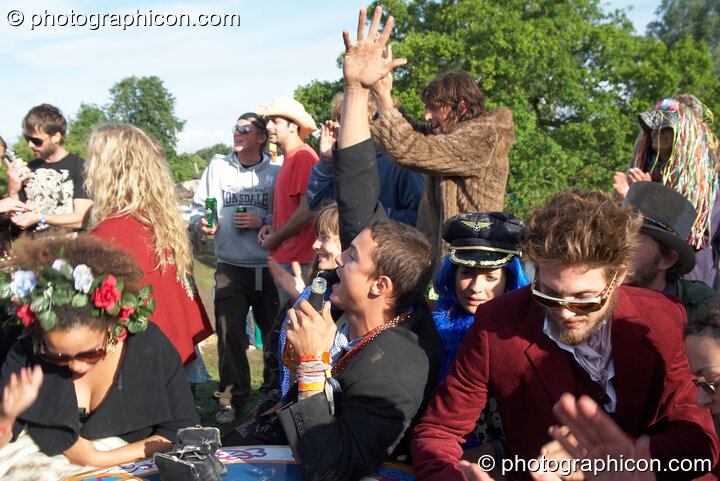 A group of wonky people gather round a table in the early morning sun at the Secret Garden Party 2007. Huntingdon, Great Britain. © 2007 Photographicon