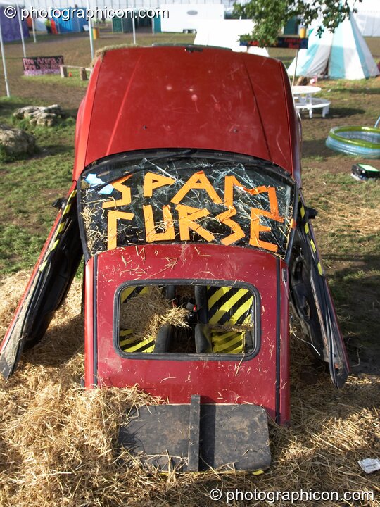 The front half of a car sticks out of the ground as site decoration at the Secret Garden Party 2007. Huntingdon, Great Britain. © 2007 Photographicon