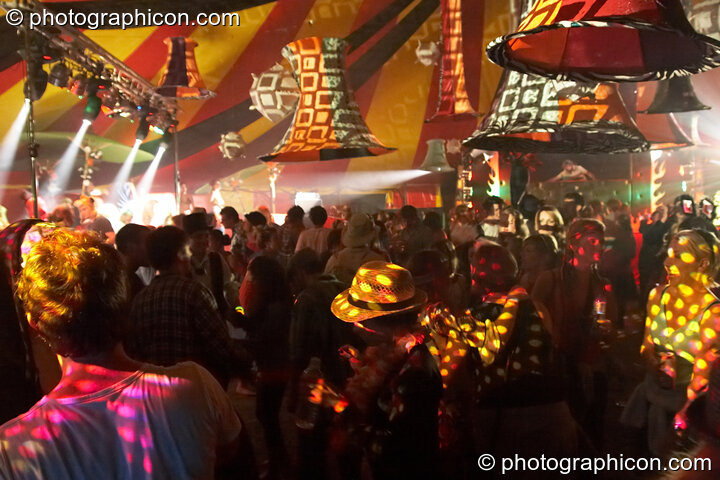 People illuminated by patterned lighting dance beneath large lamp shades in the Fish Seeks Bicycle tent at the Secret Garden Party 2008. Huntingdon, Great Britain. © 2008 Photographicon