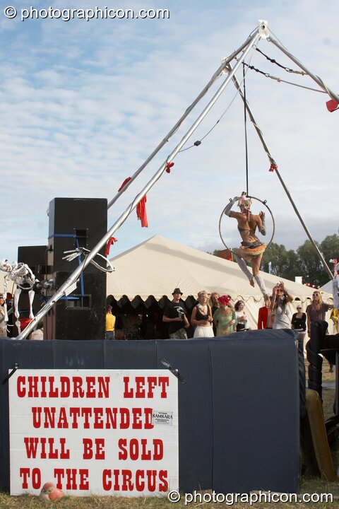 A woman performs acrobatics near a warning sign at the Secret Garden Party 2010. Huntingdon, Great Britain. © 2010 Photographicon