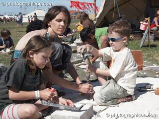 A mother supervises while her children enjoy masonic play with chalk blocks in the Crafts Field at Sunrise Celebration 2007. Yeovil, Great Britain. © 2007 Photographicon