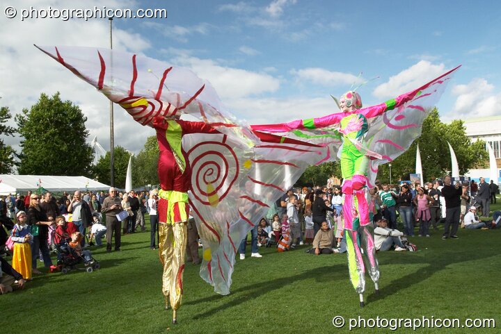 Women wearing bright winged costumes gracefully dance on stilts at the Thames Festival 2004. London, Great Britain. © 2004 Photographicon