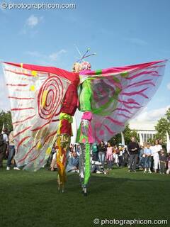 Women wearing bright winged costumes gracefully dance on stilts at the Thames Festival 2004. London, Great Britain. © 2004 Photographicon