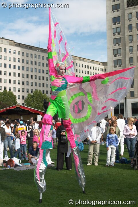 Women wearing bright winged costumes gracefully dance on stilts at the Thames Festival 2004. London, Great Britain. © 2004 Photographicon