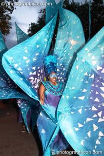 Woman in a blue petal sculpted dress performs in the night carnival at the Thames Festival 2004. London, Great Britain. © 2004 Photographicon
