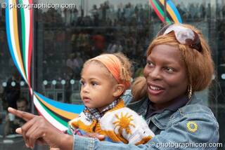 Profile of an Afro-Caribean mother and baby daughter watching a performance at the Thames Festival 2005. London, Great Britain. © 2005 Photographicon