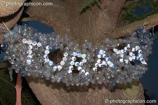 Word sculpture made of old water bottles hanging in a tree at the Turaya Gathering 2004. Wimborne, Great Britain. © 2004 Photographicon