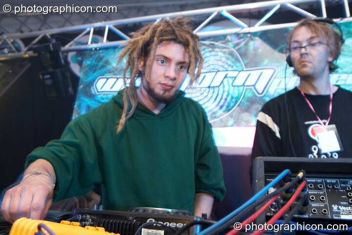 Ed Tangent DJs in the background as a VJ works on the Waveform main stage at Waveform Project 2007. Kenton, Exeter, Great Britain. © 2007 Photographicon