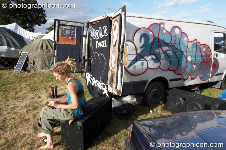 A woman sits outside the back of a graffiti painted van at Waveform Project 2007. Kenton, Exeter, Great Britain. © 2007 Photographicon