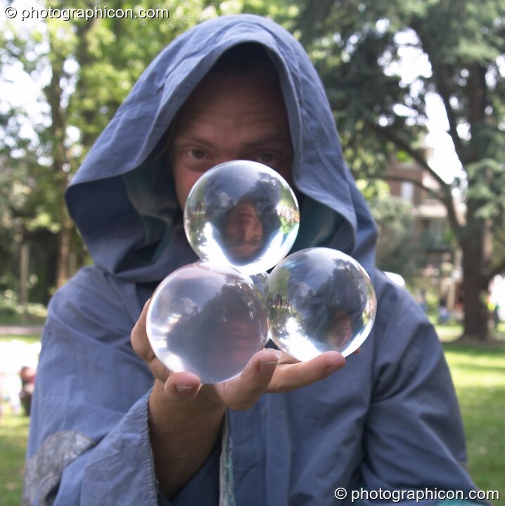 Man in robe does flowing tricks with four clear juggling balls at Kingston Green Fair 2004. Kingston Upon Thames, Great Britain. © 2004 Photographicon