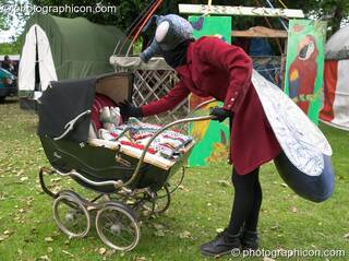 Woman wearing insect costume tends to her offspring while on walkabout at Kingston Green Fair 2005. Kingston Upon Thames, Great Britain. © 2005 Photographicon