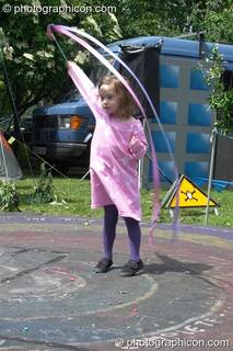 A small girl in pink plays poi at Kingston Green Fair 2005. Kingston Upon Thames, Great Britain. © 2005 Photographicon