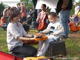 Surrey Strings encourages a child to play violin at Kingston Green Fair 2005. Kingston Upon Thames, Great Britain. © 2005 Photographicon