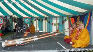Tibetan monks of Tashi-Lhumpo perform with very long horns in the Sacred Dance tent at Kingston Green Fair 2007. Kingston upon Thames, Great Britain. © 2007 Photographicon