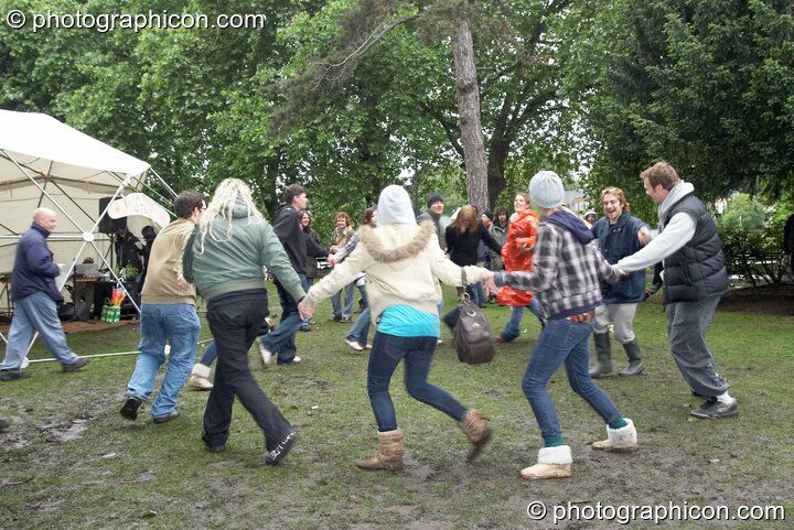 A happy group of young people dance in a circle despite the mud and rain at Kingston Green Fair 2007. Kingston upon Thames, Great Britain. © 2007 Photographicon