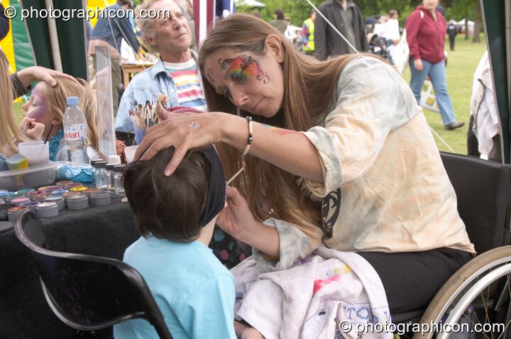 A lady in a wheelchair painting children's faces at the London Green Lifestyle Show 2005. Great Britain. © 2005 Photographicon