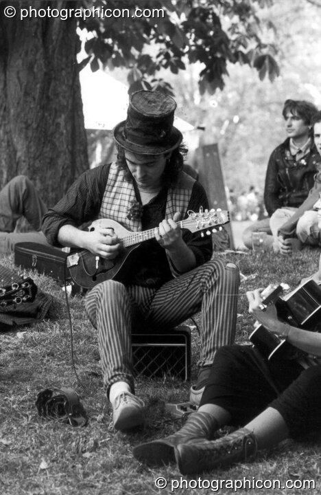A man plays a relaxing tune under a tree at the first Kingston Green Fair in 1987. Kingston upon Thames, Great Britain. © 1987 Photographicon