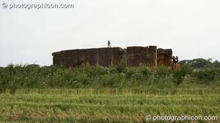 A person stands on top of a giant hay stack at the Echo Festival. Overton, Great Britain. © 2007 Photographicon